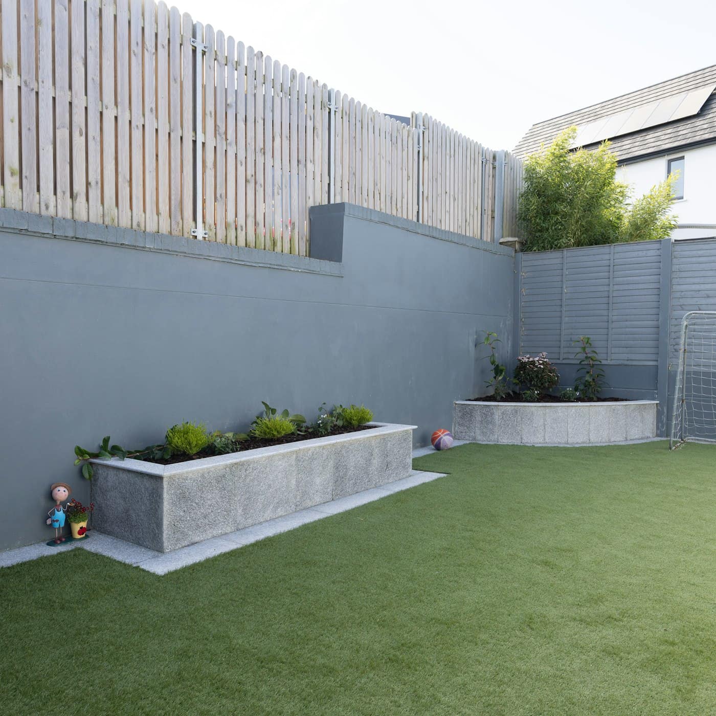 Artificial grass installed in a modern backyard with planters and patio tile
